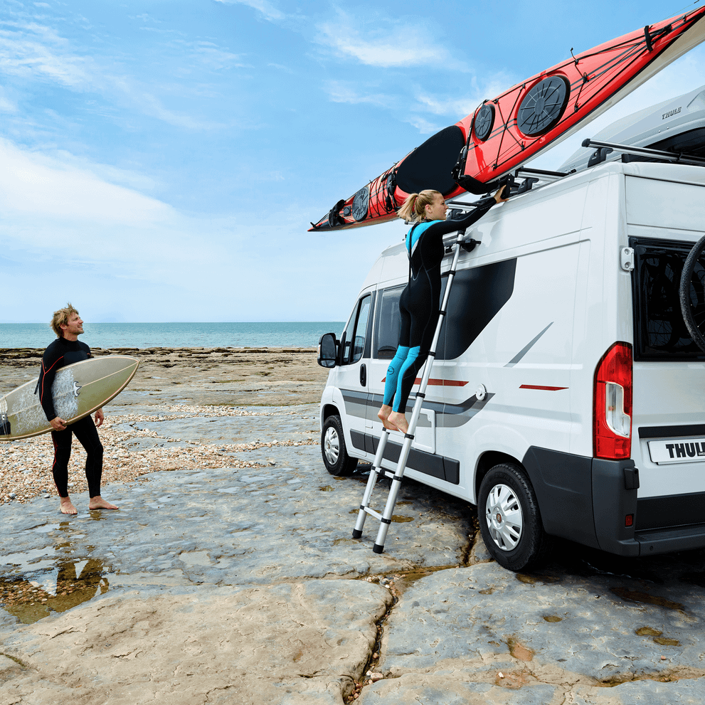 Paddler loading a kayak onto a Thule roof carrier