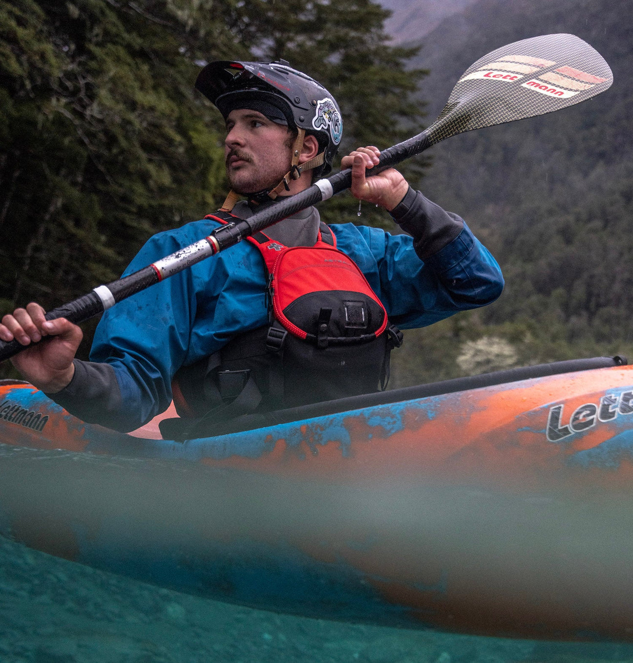 Paddler wearing an Astral life jacket in a whitewater kayak