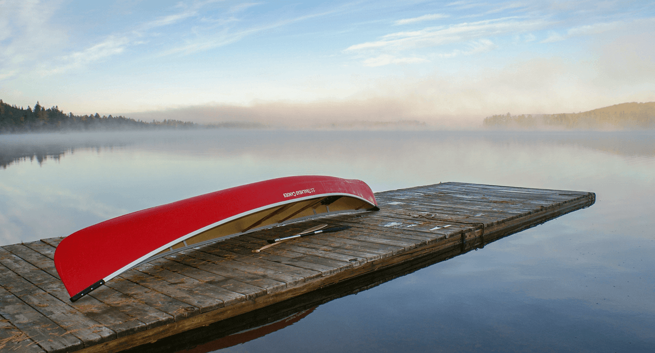 Trailhead Canoes red canoe resting on a dock beside a calm lake